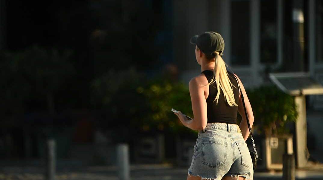 Νεαρή με καπέλο περπατά στο κέντρο της Αθήνας