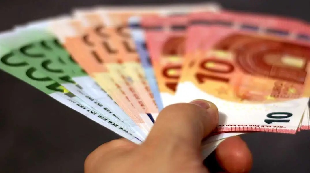 Χέρι κρατά χαρτονομίσματα ευρώ