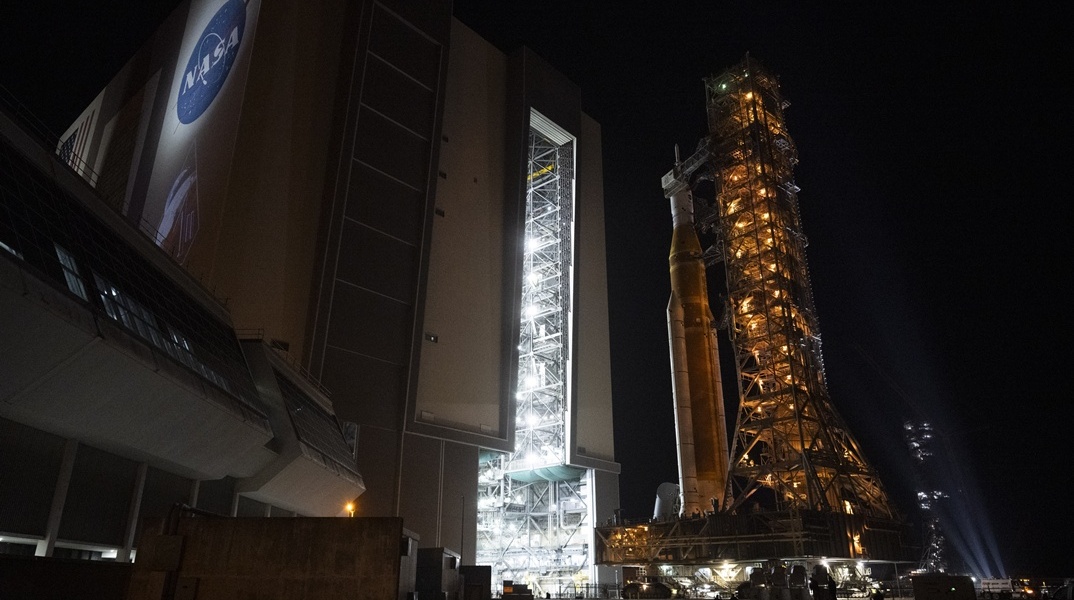 Μια φωτογραφία που διατέθηκε από τη NASA δείχνει τον πύραυλο Space Launch System (SLS) της NASA και το διαστημόπλοιο Orion, στερεωμένα στον κινητό εκτοξευτή, καθώς εκκινεί από το Κτίριο Συναρμολόγησης Οχημάτων προς την Εξέδρα Εκτόξευσης 39Β, στο Διαστημικό Κέντρο Κένεντι της NASA