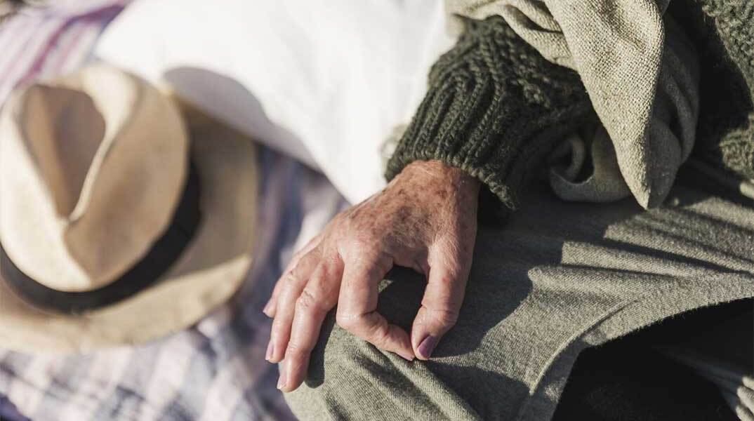 Χέρι ηλικιωμένου ακουμπισμένο στο πόδι