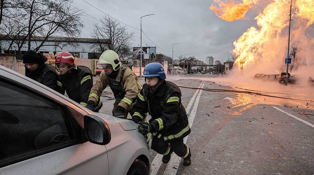 Πυροσβέστες στο Κίεβο απομακρύνουν σταθμευμένο αυτοκίνητο από πυρκαγιά που ξέσπασε μετά τη ρωσική επίθεση με πύραυλο