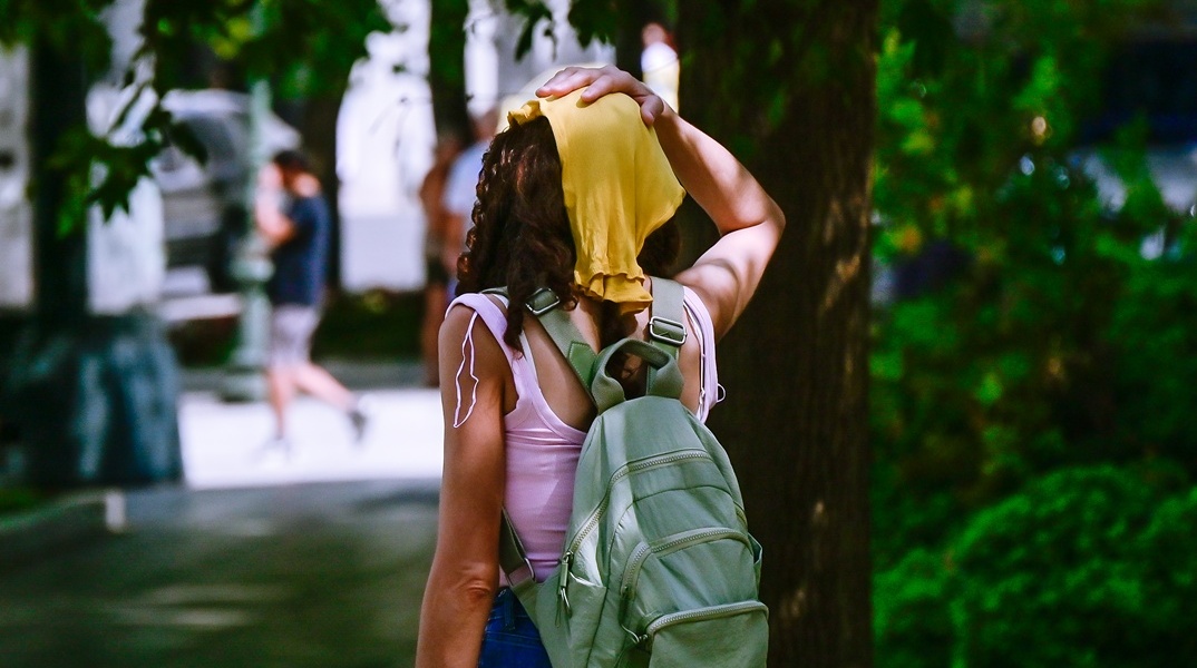 Γυναίκα με βρεγμένο πανί στο κεφάλι προσπαθεί να αντιμετωπίσει τις συνθήκες καύσωνα