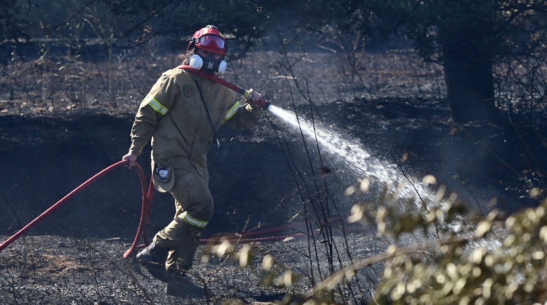 Πυροσβέστης με τη μάνικα ανά χείρας επιχειρεί για την κατάσβεσης φωτιάς