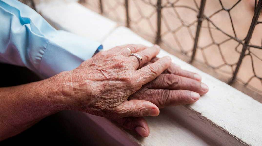 Ηλικιωμένοι στο παράθυρο ακουμπούν ο ένας το χέρι του άλλου