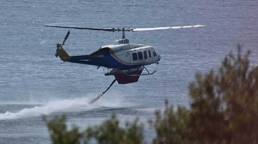 Ελικόπτερο γεμίζει νερό από τη θάλασσα για να το ρίξει σε δασική πυρκαγιά