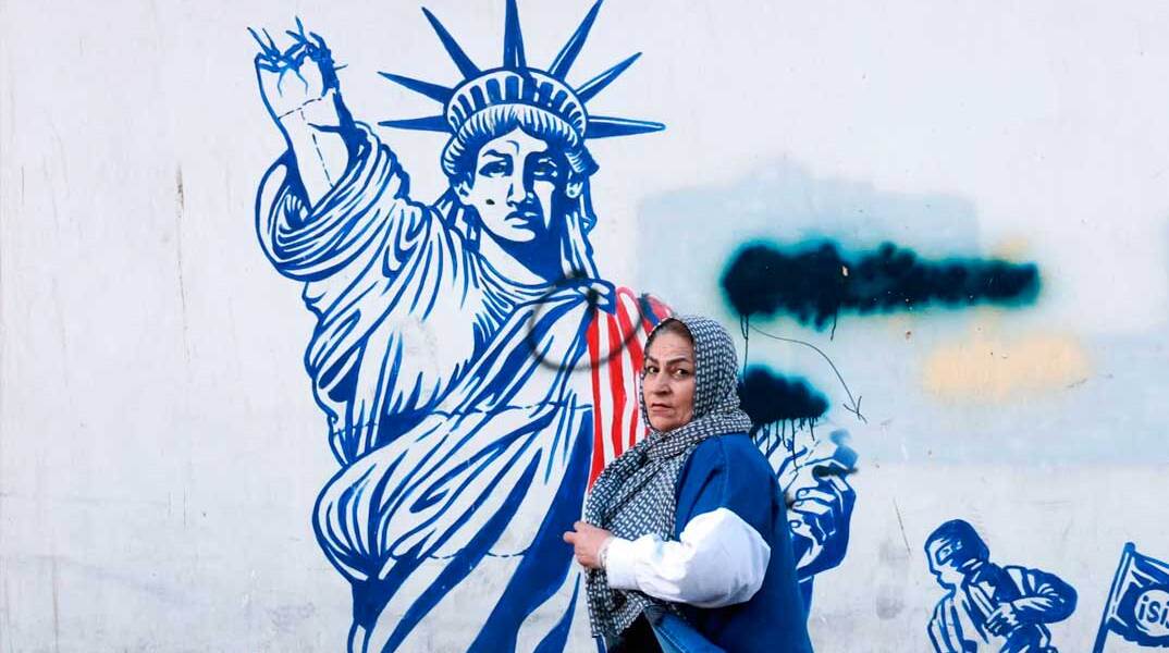 Γυναίκα περνά μπροστά από mural στην Τεχεράνη  με το άγαλμα της Ελευθερίας