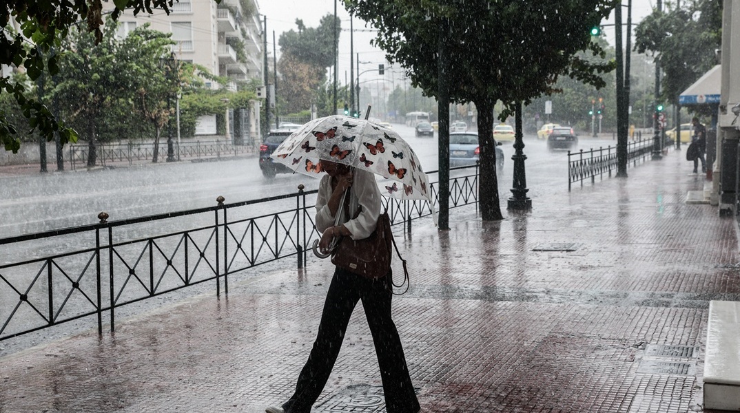 Γυναίκα με ομπρέλα εν μέσω μπουρινιού στο κέντρο της Αθήνας