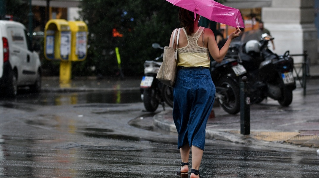 Γυναίκα με ομπρέλα εν μέσω καλοκαιρινού μπουρινιού