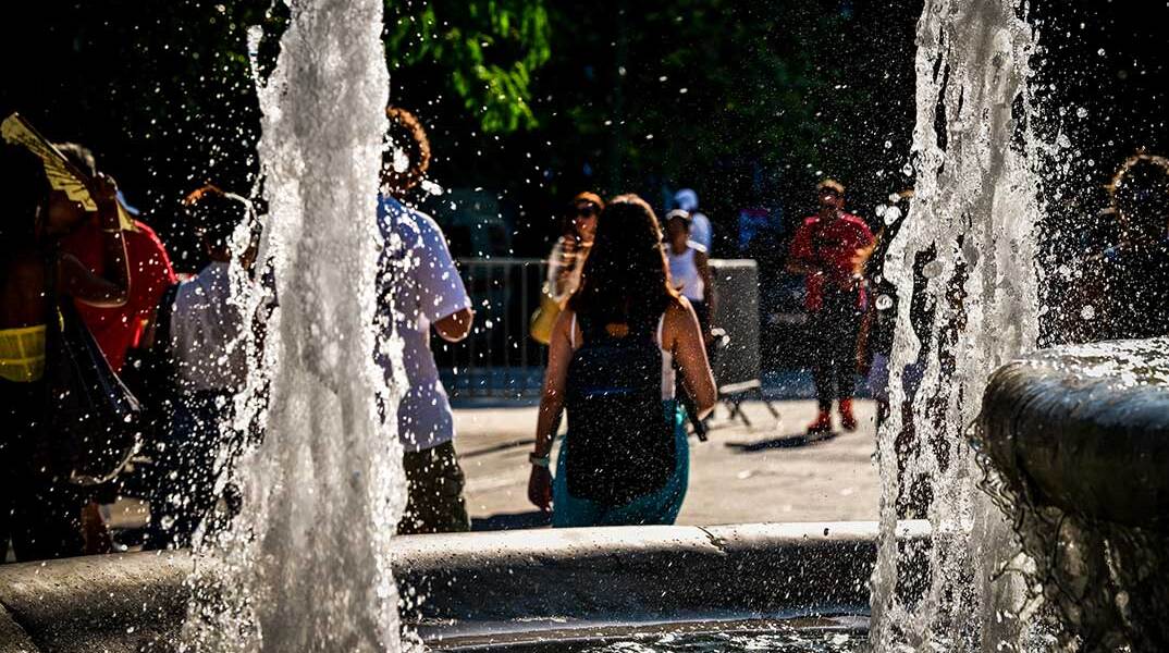 Κόσμος περνά μπροστά από το συντριβάνι στην πλατεία Συντάγματος