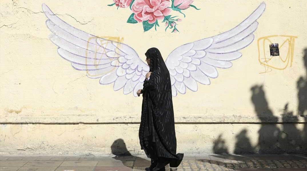 Γυναίκα στο Ιράν περνά μπροστά από mural στην πρωτεύουσα Τεχεράνη