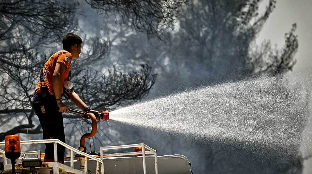 Πυροσβέστης ρίχνει νερό σε δασική πυρκαγιά