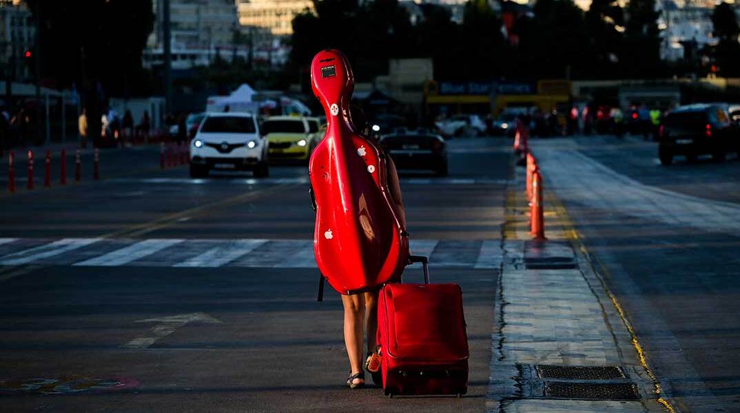 Ταξιδιώτης με μουσικό όργανο στην πλάτη στο λιμάνι Πειραιά