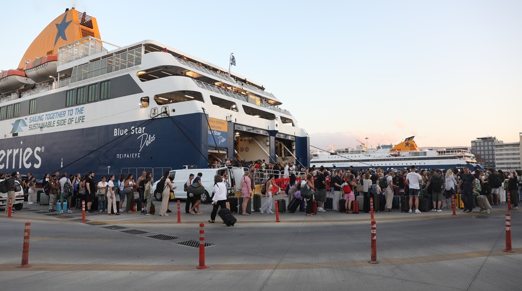 Ταξιδιώτες μπροστά από τον καταπέλτη πλοίου στο λιμάνι του Πειραιά