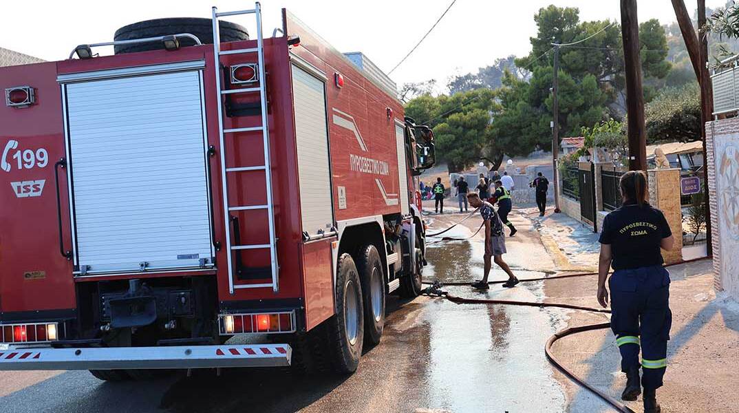 Πυροσβέστες σβήνουν τη φωτιά στη Σαλαμίνα, η οποία απειλεί κατοικίες