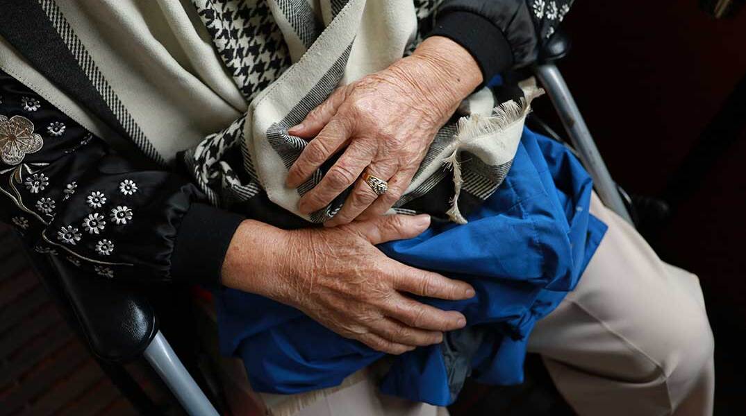 Ηλικιωμένη κρατά ρούχα στα χέρια 