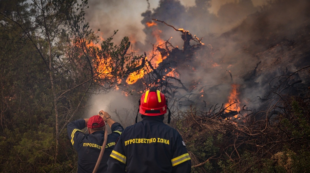 Πυροσβέστης με τη μάνικα ανά χείρας επιχειρεί για την κατάσβεσης φωτιάς