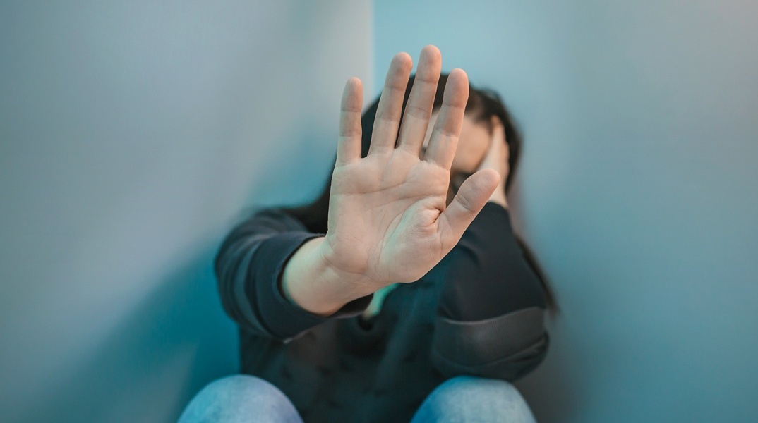 Γυναίκα που προτάσσει το χέρι της για να κρύψει το πρόσωπό της