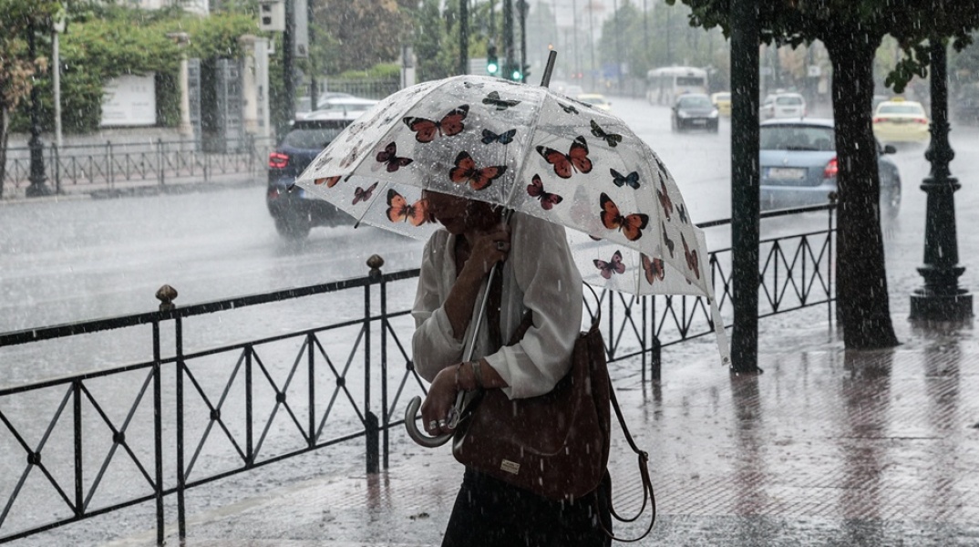 Γυναίκα κρατά ομπρέλα εν μέσω ισχυρής καταιγίδας