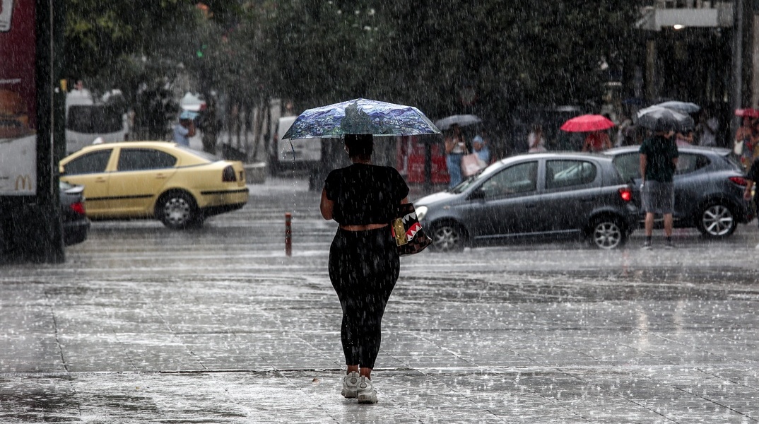 Γυναίκα με ομπρέλα εν μέσω καταιγίδας