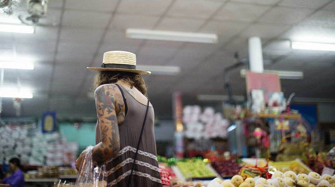 Γυναίκα με ψάθινο καπέλο ψωνίζει στο σούπερ μάρκετ