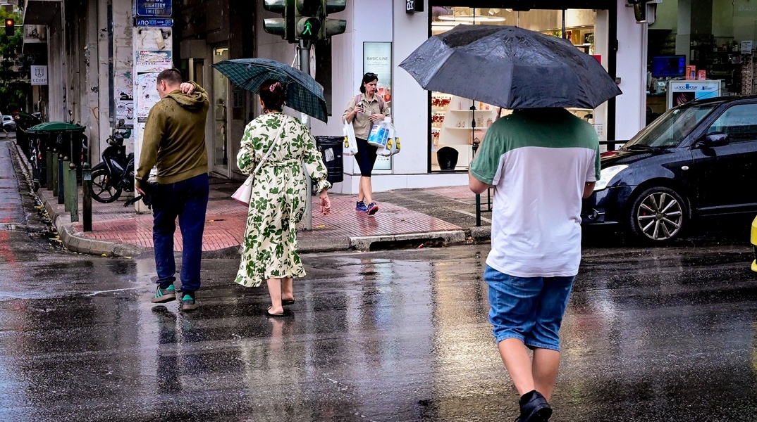 Πολίτες με ομπρέλες εν μέσω βροχής