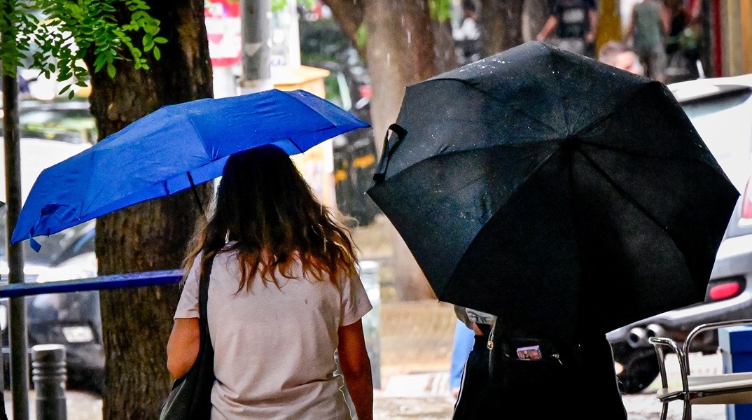 Πολίτες με ομπρέλες εν μέσω καταιγίδας