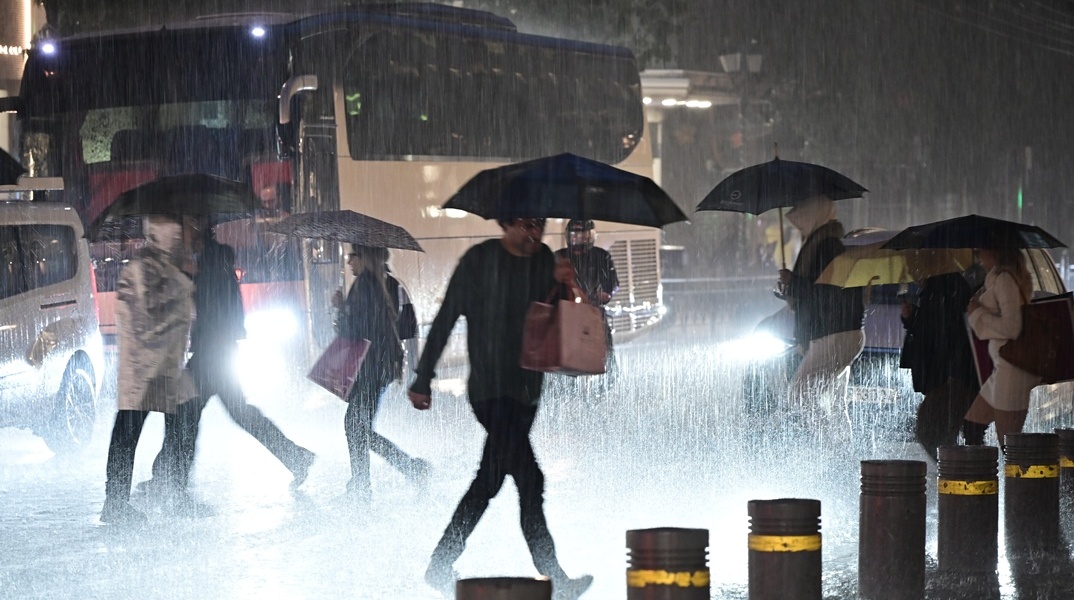 Πολίτες περπατούν στον δρόμο, μπροστά από οχήματα εν μέσω κακοκαιρίας - καταιγίδας
