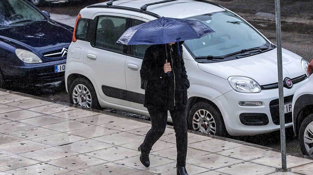 Γυναίκα με ομπρέλα εν μέσω κακοκαιρίας στην Αττική