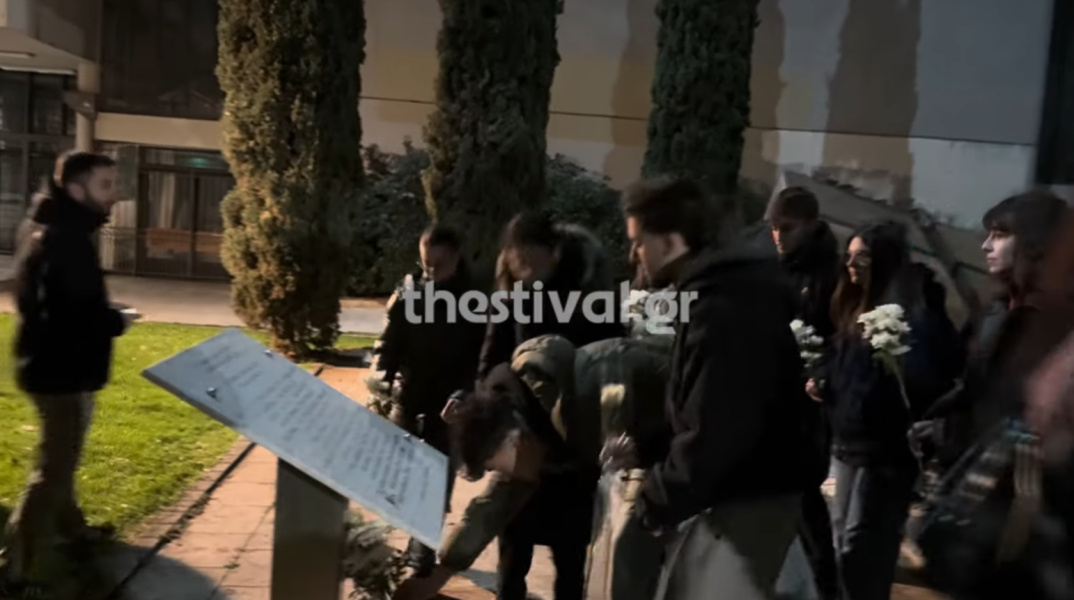 Φοιτητές αφήνουν στο μνημείο λίγα λουλούδια για τα θύματα της σιδηροδρομικής τραγωδίας στα Τέμπη