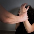 Άνδρας κρατά το χέρι γυναίκας που κρύβει το πρόσωπό της για να αποφύγει επίθεση