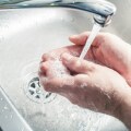 Βρύση που τρέχει νερό και άτομο που πλένει τα χέρια του