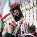 Διαδηλωτές με τη φωτογραφία του Μοτζταμπά Χαμενεΐ και ιρανικές σημαίες στο Παρίσι | 14 Μαρτίου 2026 © Vincent Koebel/NurPhoto via Getty Images