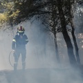 Πυροσβέστης με τη μάνικα ανά χείρας πίσω από καπνούς εν μέσω κατάσβεσης φωτιάς