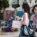 Γυναίκα με τσάντα περνά έξω από κατάστημα εν μέσω εκπτώσεων