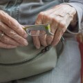 Ηλικιωμένη κρατά γυαλιά πρεσβυωπίας και τσάντα στα χέρια