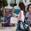 Νεαρή με τσάντες και ψώνια περνά έξω από κατάστημα