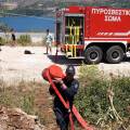 Πυροσβέστης μεταφέρει μάνικα μπροστά από πυροσβεστικό όχημα