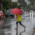Γυναίκα με ομπρέλα και γαλότσες εν μέσω κακοκαιρίας