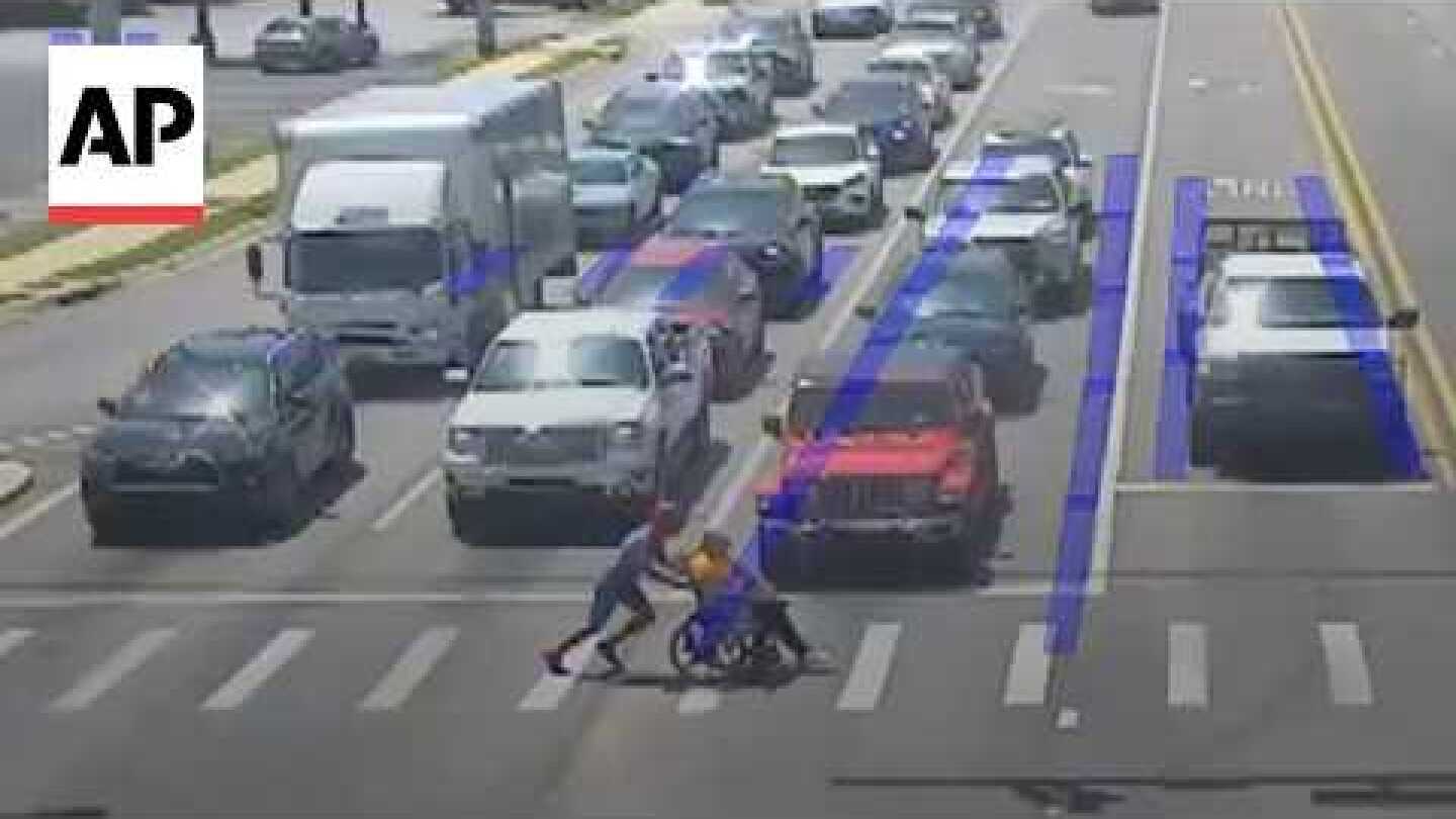Man dressed as Spider-Man helps a person in a wheelchair cross the road
