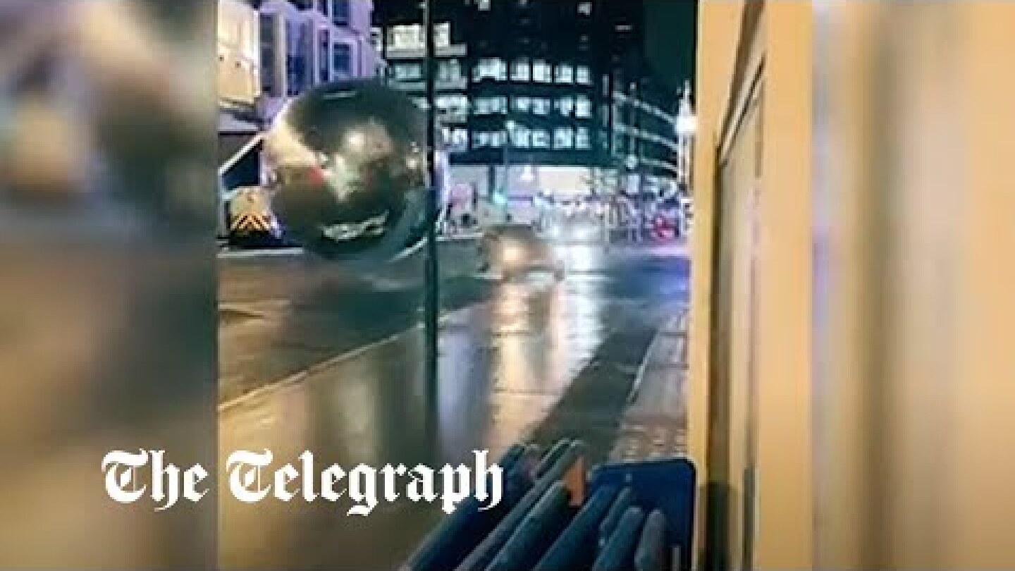 Cars dodge massive baubles rolling down central London street