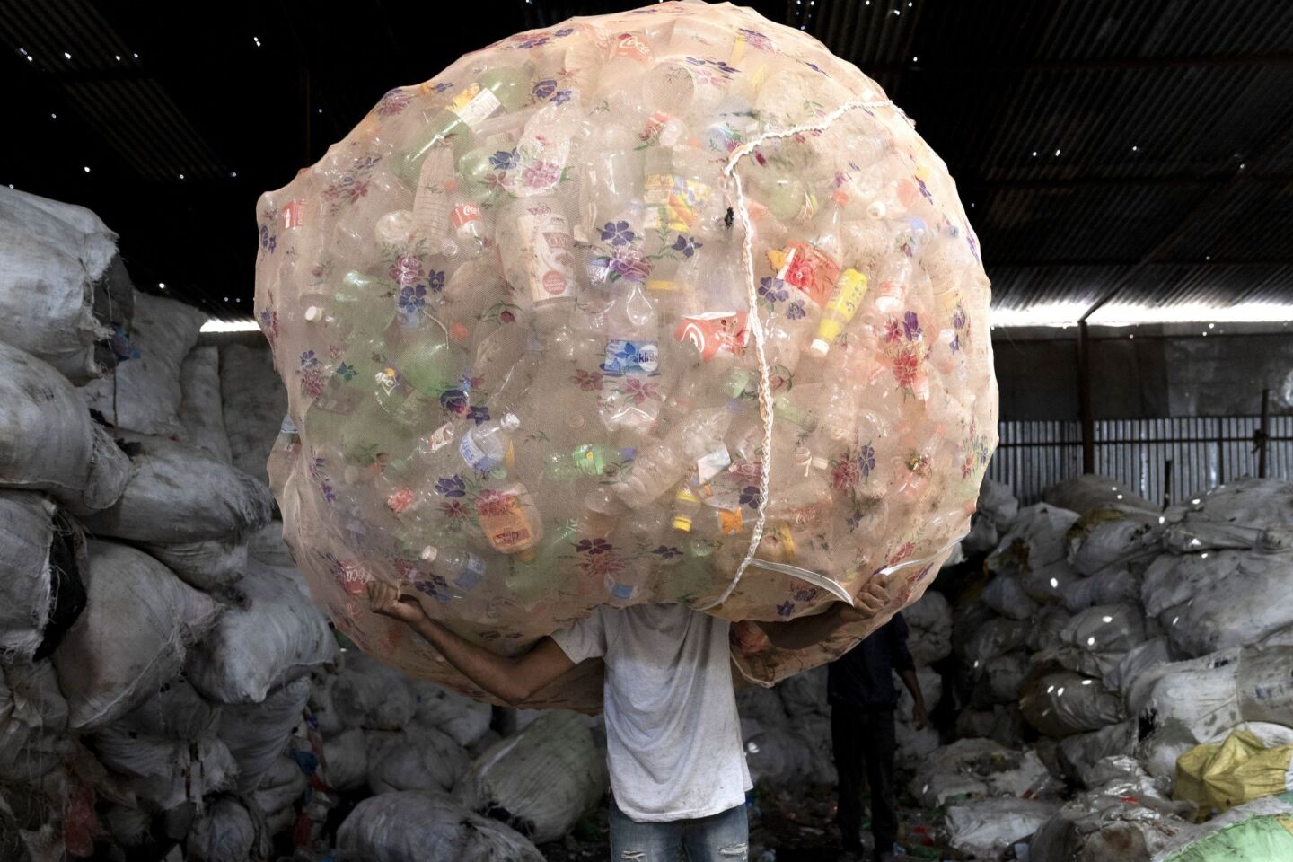 Ένας εργαζόμενος μεταφέρει δέσμες με μπουκάλια PET (τερεφθαλικό πολυαιθυλένιο) 