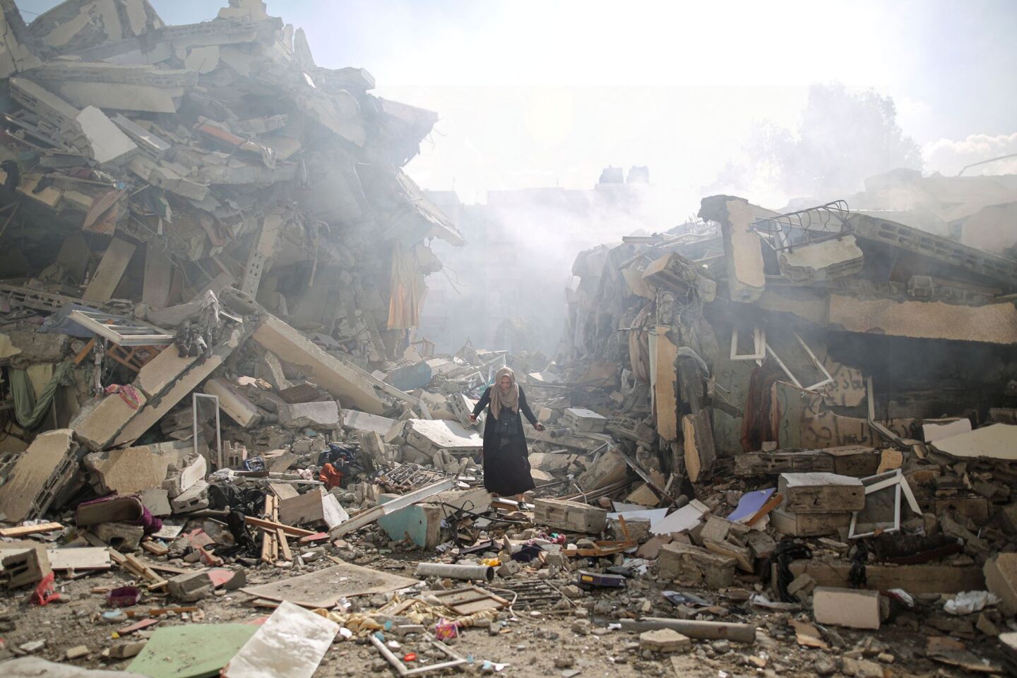 Γυναίκα περπατά ανάμεσα στα ερείπια κτιρίων και κατοικιών μετά τις ισραηλινές αεροπορικές επιδρομές στη Γάζα