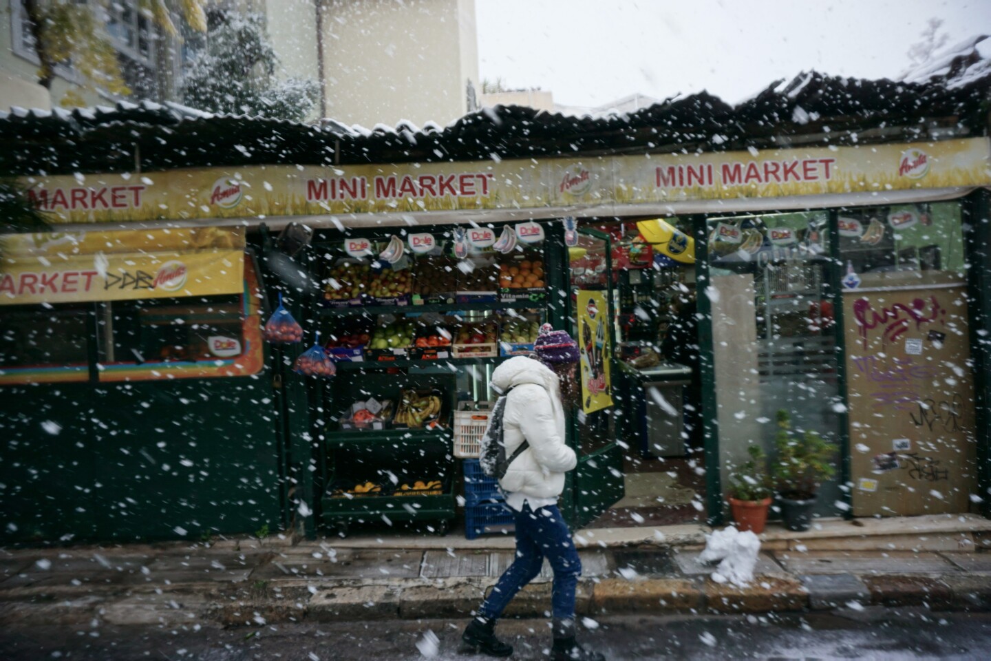 Ένας άνθρωπος περπατάει στην χιονισμένη Αθήνα. 