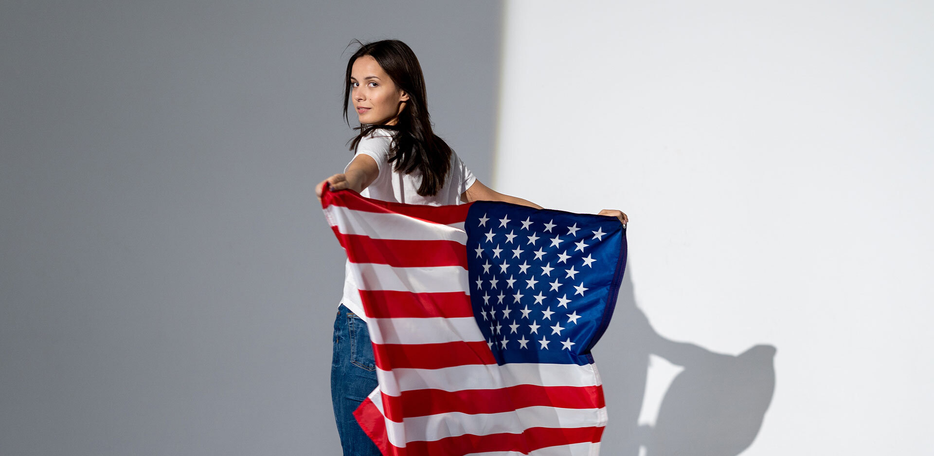 Γυναίκα με λευκό μπλουζάκι και τζιν, που κρατάει την αμερικάνικη σημαία