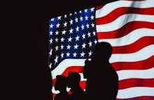 Φιγούρεα ανθρώπων μπροστά από τη σημαία της Αμερικής