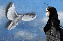 Γυναίκα με μαντίλα περνά μπροστά από mural στην Τεχεράνη