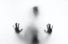 Σκιά πίσω από λευκό πανί στην οποία διακρίνονται χέρια και κεφάλι