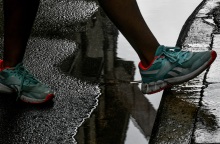 Πόδι με αθλητικό παπούτσι περνά πάω από λιμνάζοντα νερά σε δρόμο