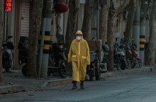 Κάτοικος στη Σανγκάη της Κίνας με αδιάβροχο και μάσκα για τον κορωνοϊό περπατά σε έρημο δρόμο της πόλης