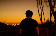 Νεαρό αγόρι με την πλάτη γυρισμένη στον φακό με το φως της δύσης του ήλιου